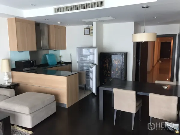 公寓 出租在Sathon, Bangkok - 开放式空间，木色橱柜的厨房与吧台，旁有餐桌和打开的冰箱。