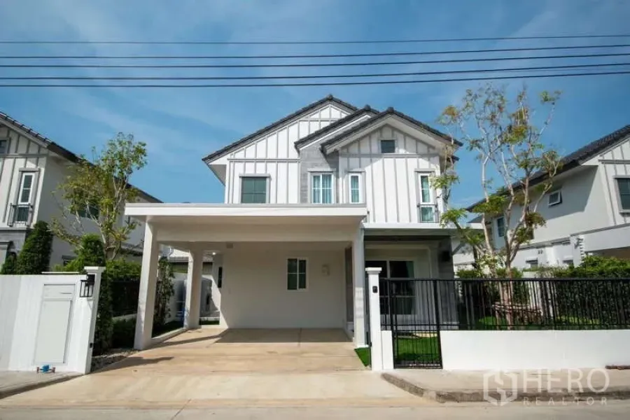 Detached House for rent in Bang Phli, Samut Prakan - Modern two-storey detached house with white facade, gated front yard and covered carport.