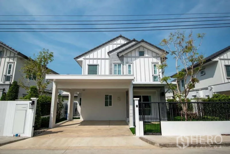Detached House for rent in Bang Phli, Samut Prakan - Modern two-storey detached house with white facade, gated front yard and covered carport.