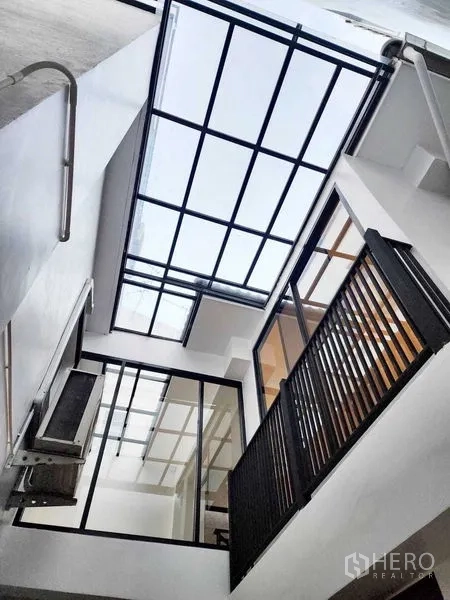 带办公室的家 出租或出售在Watthana, Bangkok - 中央天井配玻璃屋顶与黑框窗，引入充足自然光。