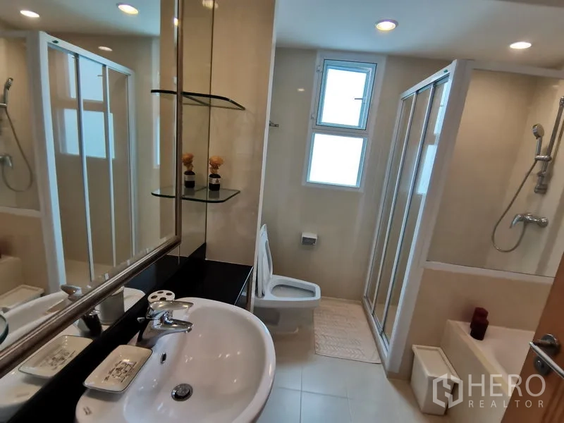 公寓 出租在Khlong Toei, Bangkok - 浅色瓷砖卫浴，带洗手台、玻璃淋浴间及独立浴缸。