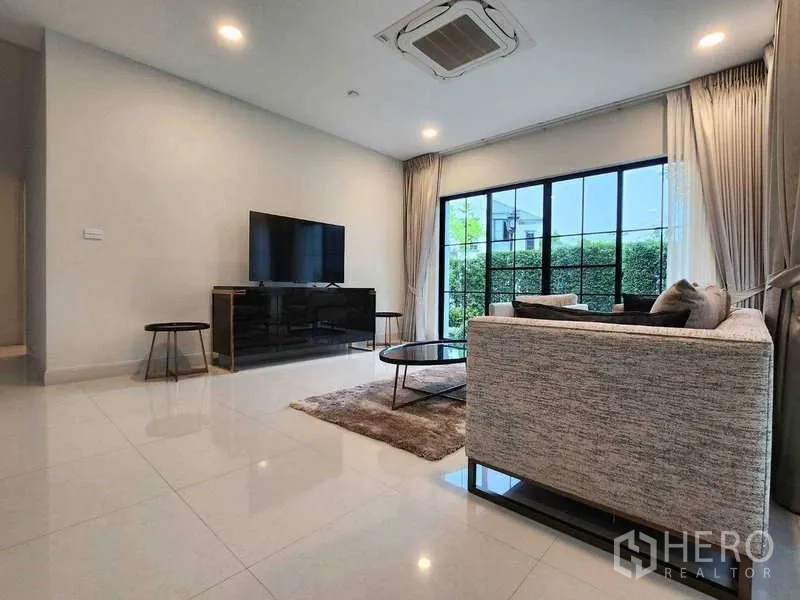 Detached House for rent in Saphan Sung, Bangkok - Family room with TV console, sofa set and floor-to-ceiling sliding doors to greenery.