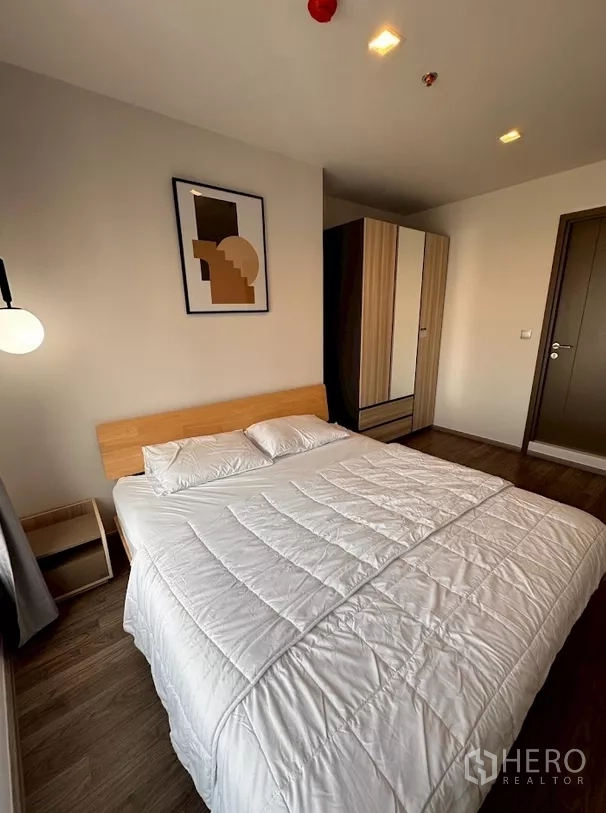 Condominium for rent in Chatuchak, Bangkok - Bedroom with white bedding, wardrobe and door to hallway.