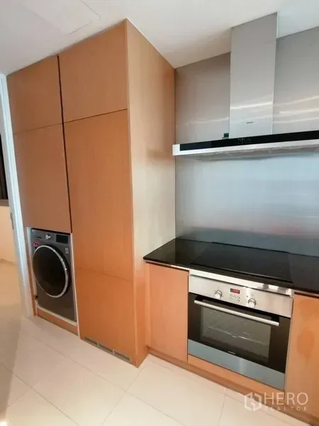 Condominium for sale in Yan Nawa, Bangkok - Modern kitchen featuring built-in oven, cooktop, stainless-steel hood and washer-dryer.