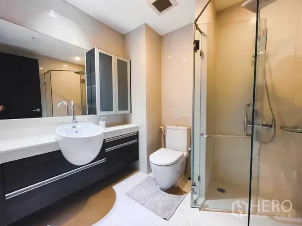 公寓 出租在Watthana, Bangkok - 现代卫浴，宽大镜面与洗手台，坐便器及玻璃淋浴间。