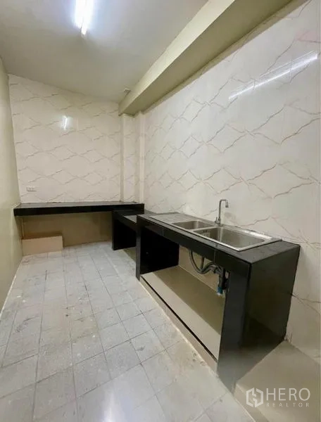 Townhouse for rent - Functional Thai kitchen with dual sink, black counters and tiled backsplash.
