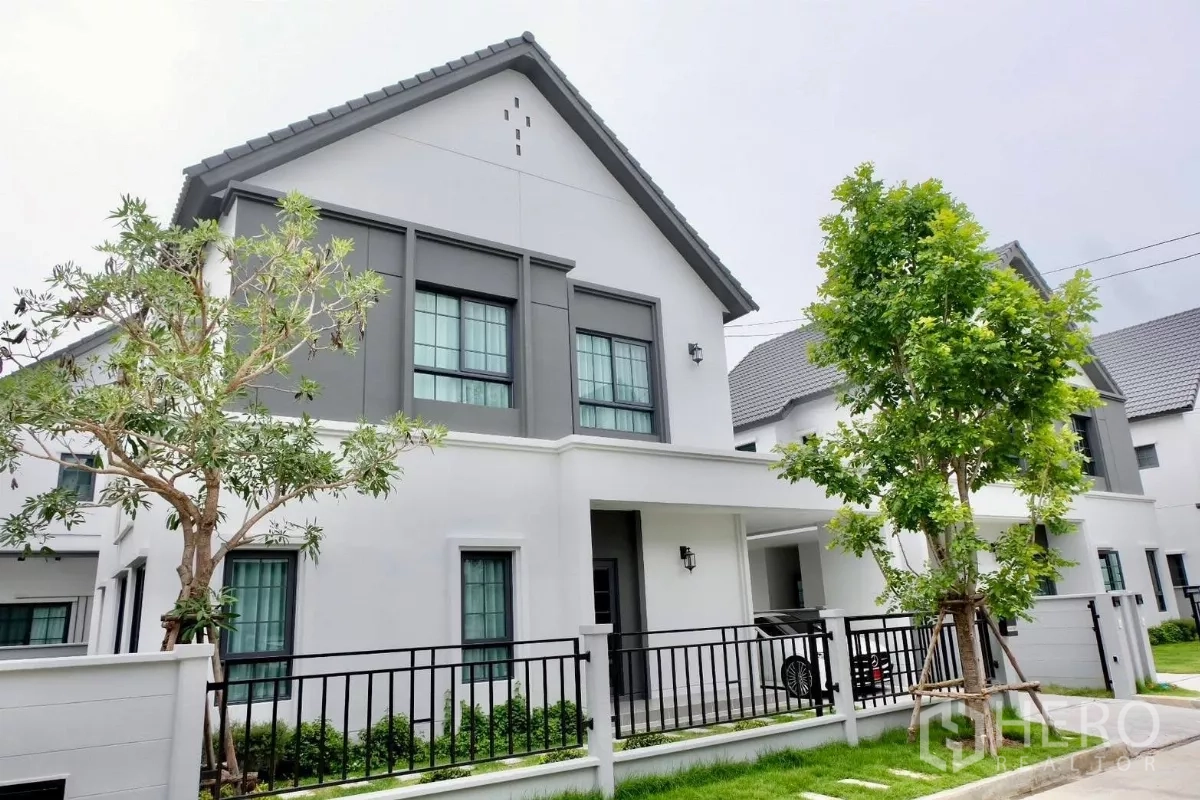 Detached House for sale in Bang Phli, Samut Prakan - Corner exterior view of a two-storey modern detached house with pitched roof, green lawn and front fence