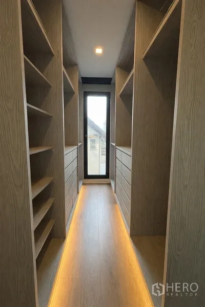 Semi-detached House for rent in Watthana, Bangkok - Narrow walk-in closet with window and illuminated shelving.