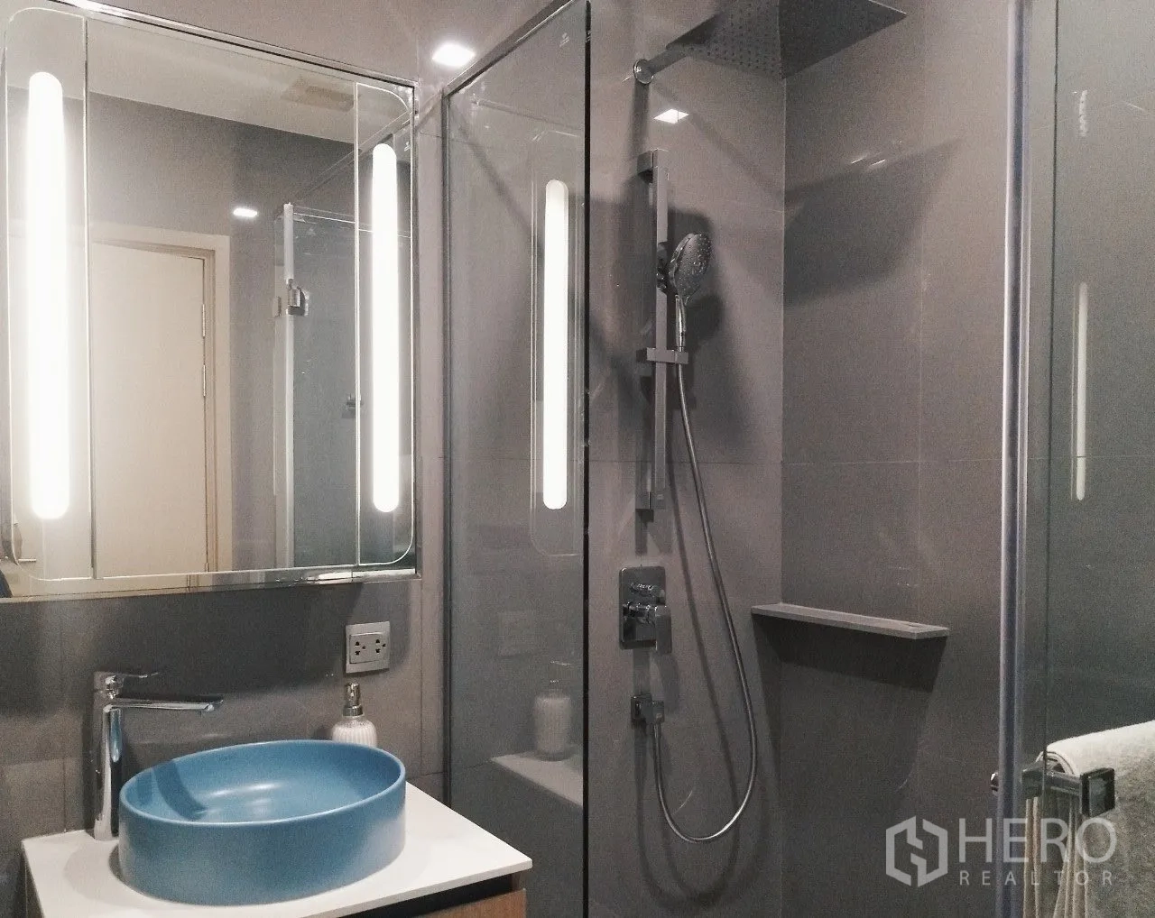 公寓 for rent in Watthana, Bangkok - 玻璃淋浴间配雨淋花洒，旁有带灯镜与蓝色台上盆。