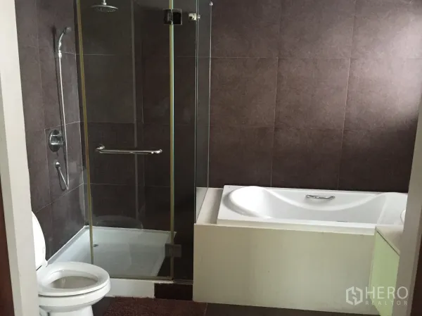 Condominium for rent in Watthana, Bangkok - Modern bathroom featuring a glass-enclosed shower, separate bathtub, and contemporary tiled walls.