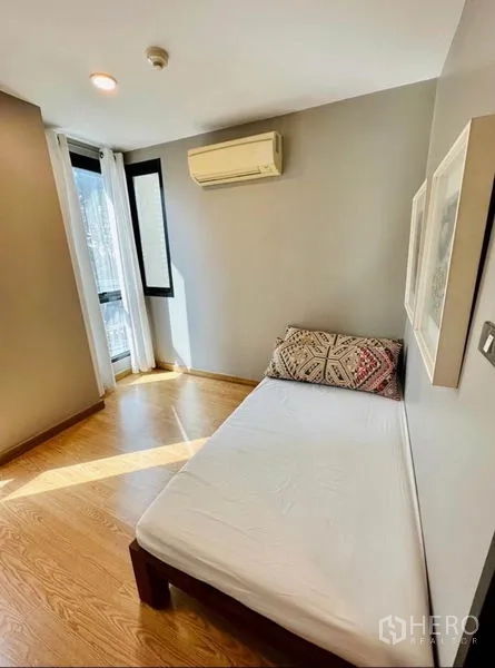Condominium for rent in Watthana, Bangkok - Bright second bedroom with single bed, air conditioner and corner windows.