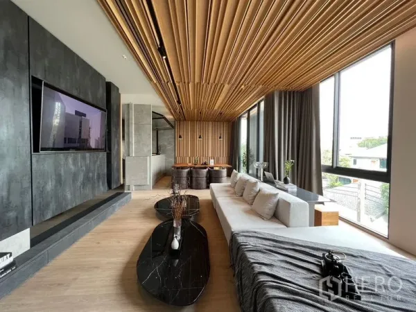 Home Office for sale in Prawet, Bangkok - Stylish living lounge featuring a wood-slat ceiling, large sofa, and black marble coffee tables.