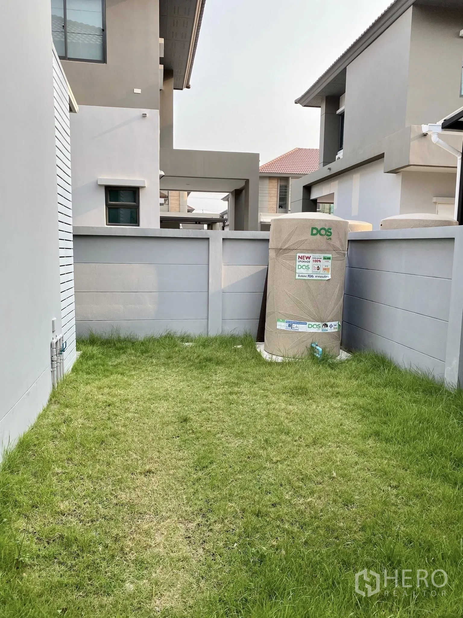 Detached House for sale in Saphan Sung, Bangkok - Backyard lawn with water tank and high privacy wall.