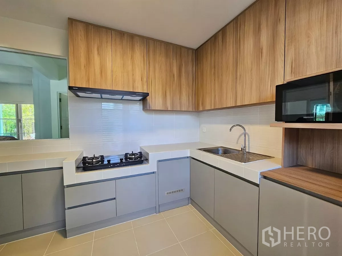 Detached House for rent in Bang Phli, Samut Prakan - Fully equipped L-shaped kitchen with gas hob, hood, wood-grain cabinets and sink.