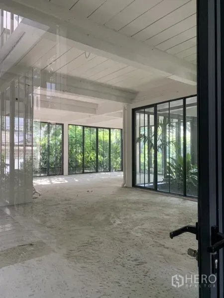 Office Space for rent in Khlong Toei, Bangkok - Bright open interior with white ceiling beams and expansive windows overlooking gardens.