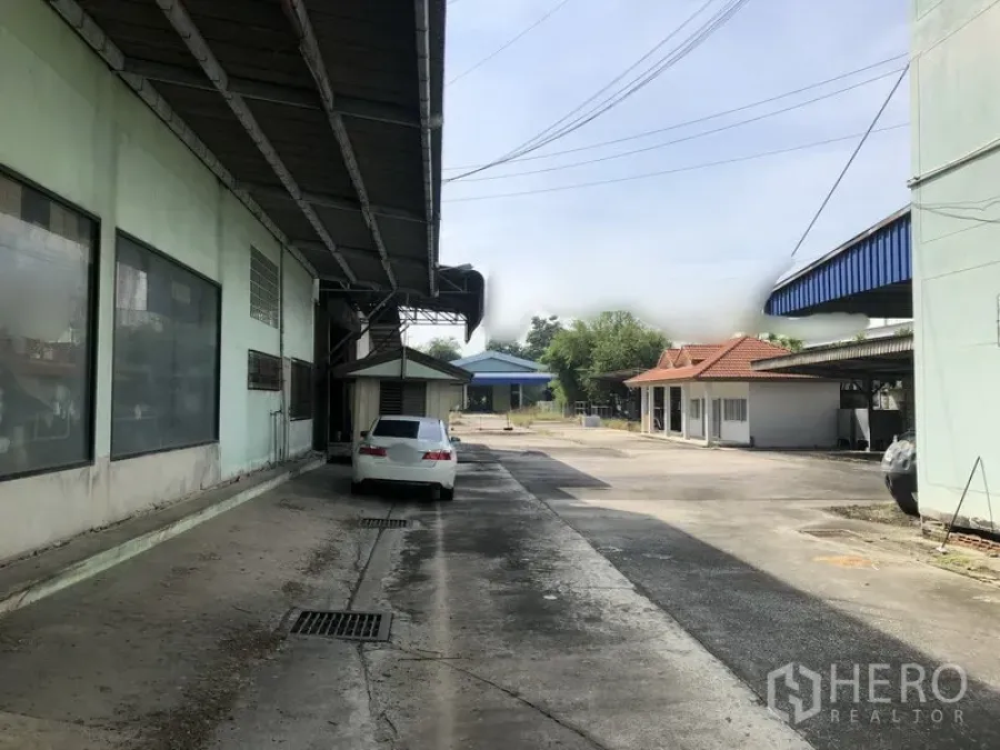 货栈 出租或出售在Lam Luk Ka, Pathum Thani - 仓库侧边带顶装卸通道，车道上停有一辆汽车。