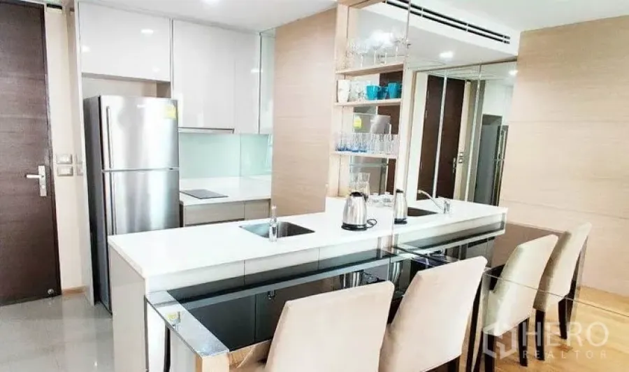 คอนโด ให้เช่าในRatchathewi, Bangkok - ครัวเปิดโทนขาว เคาน์เตอร์ยาวแบบบาร์ ตู้เย็นสแตนเลส และชุดโต๊ะอาหาร