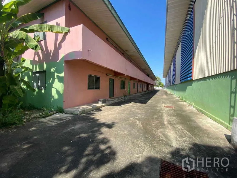 Warehouse for rent in Lat Lum Kaeo, Pathum Thani - Rear façade of pink accommodation block beside warehouse and paved walkway.