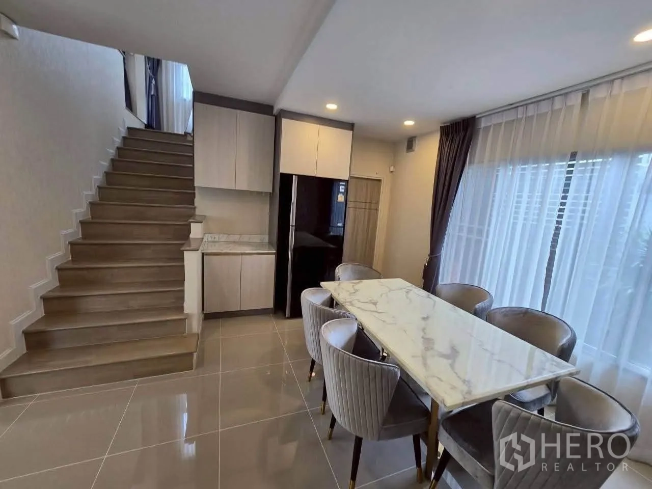 Detached House for rent or sale in Lat Krabang, Bangkok - Dining area by the stairs with marble-top table and six upholstered chairs.