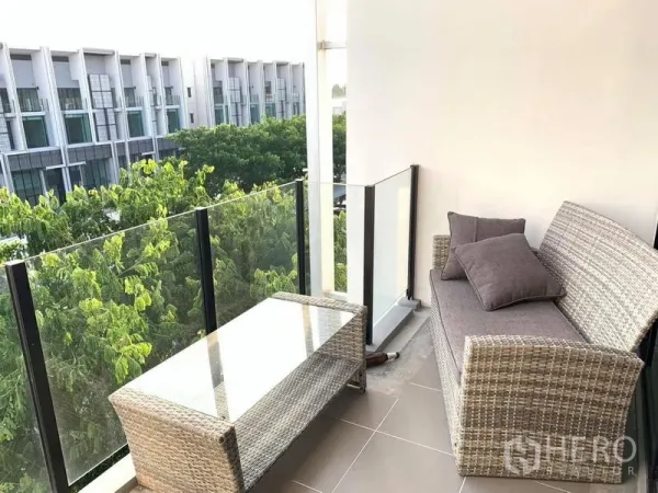 带办公室的家 出租 - 阳台设藤制沙发与玻璃桌，可眺望绿树与周边建筑景观。