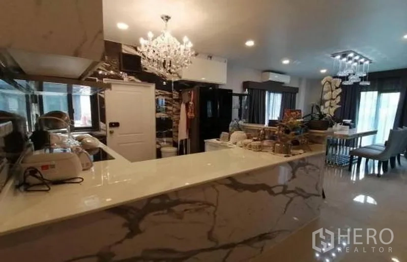 Detached House for sale in Bang Phli, Samut Prakan - Kitchen connecting to dining area under a crystal chandelier with glossy floors and ample storage.