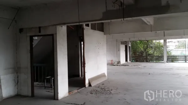 Office Space for rent in Don Mueang, Bangkok - Raw open‑plan office floor with concrete surfaces, exposed beams and large grilled windows in Don Mueang, Bangkok.
