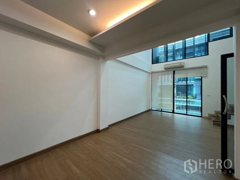 ทาวน์เฮาส์ ให้เช่าหรือขายในKhlong Toei, Bangkok - ห้องนั่งเล่นเพดานสูงโปร่ง ผนังกระจกเต็มบานและเชื่อมต่อระเบียง