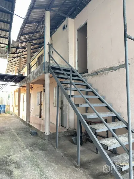 Warehouse for sale in Nong Chok, Bangkok - Metal staircase leading to second-floor staff quarters along a covered walkway beside the warehouse.
