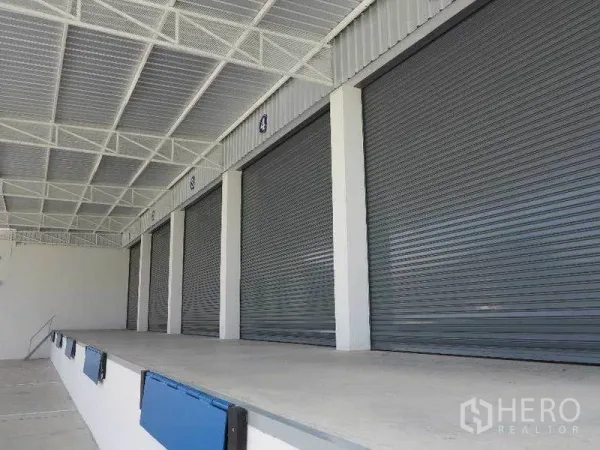 Warehouse for rent in Ban Bueng, Chon Buri - Covered loading dock with multiple roll-up doors for truck access.
