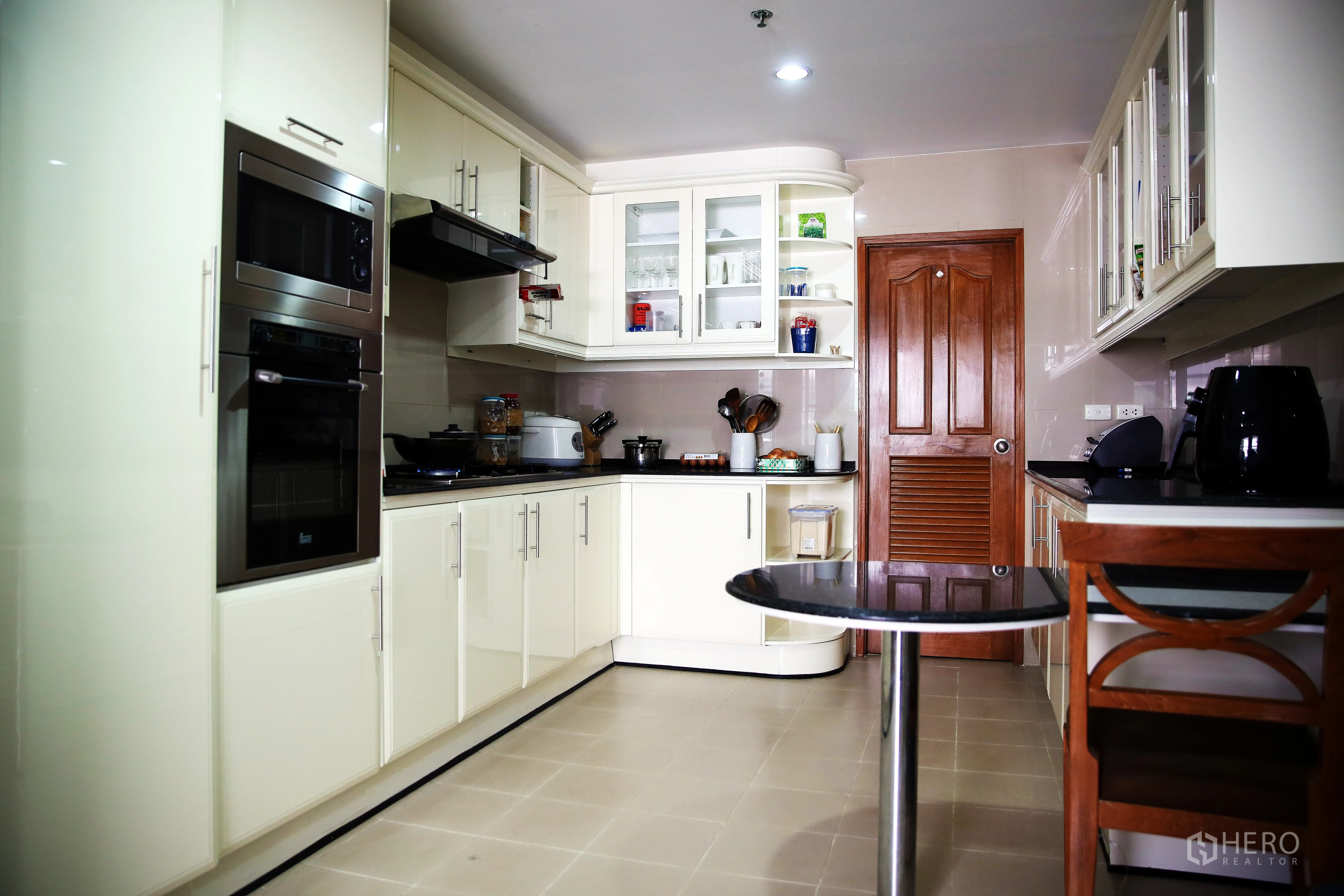 房间 出租在Khlong Toei, Bangkok - 封闭式厨房，白色橱柜，嵌入式烤箱与抽油烟机，黑色台面。