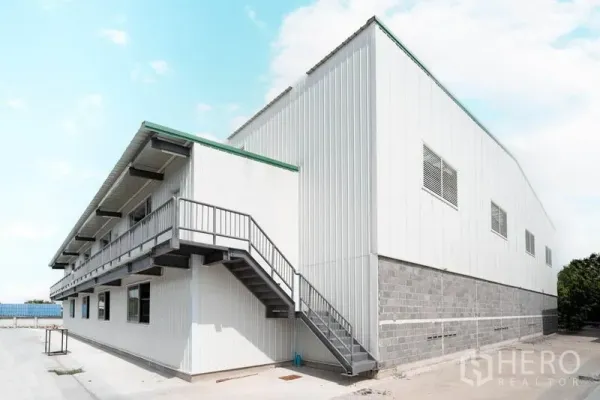 货栈 出租在Lat Krabang, Bangkok - 仓库侧立面，金属楼梯通往夹层办公室，金属板外墙与通风窗