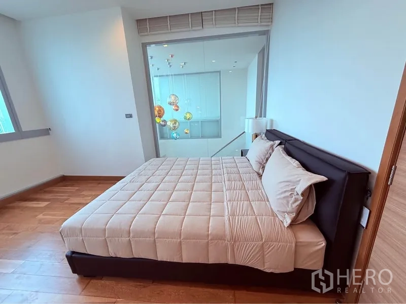 คอนโด ให้เช่าหรือขายในKhlong Toei, Bangkok - ห้องนอนแขก ผ้าปูสีเบจ มองลงสู่โถงสองชั้นและโคมไฟตกแต่ง