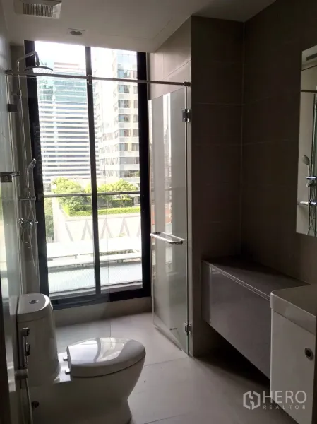 คอนโด ให้เช่าในPathum Wan, Bangkok - ห้องน้ำโมเดิร์นมีฉากกั้นอาบน้ำกระจก โถสุขภัณฑ์ และหน้าต่างบานใหญ่เห็นวิวเมือง