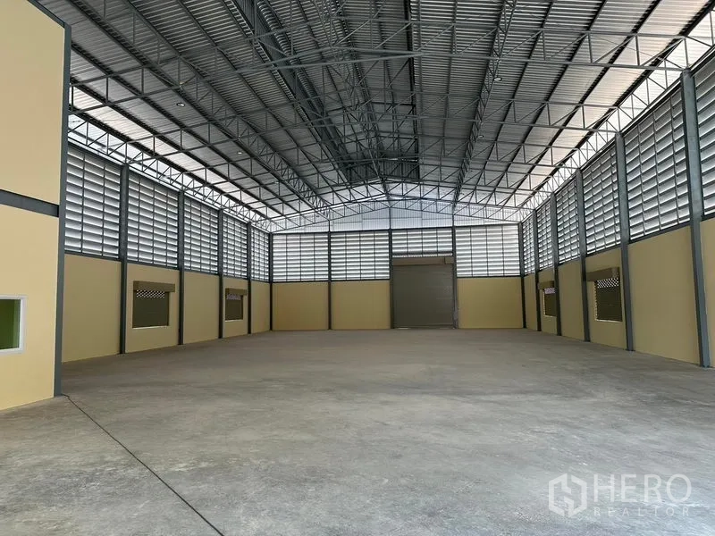 Warehouse for rent or sale in Bang Phli, Samut Prakan - Spacious warehouse interior with high steel truss roof, ventilated louvered panels and a large roller door.