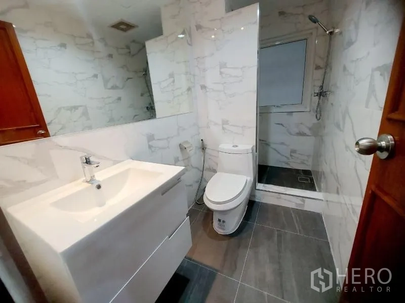 คอนโด ให้เช่าในWatthana, Bangkok - ห้องน้ำกะทัดรัด มีเคาน์เตอร์อ่างล้างหน้า โถสุขภัณฑ์ และโซนอาบน้ำ ผนังลายหินอ่อนและพื้นสีเทา