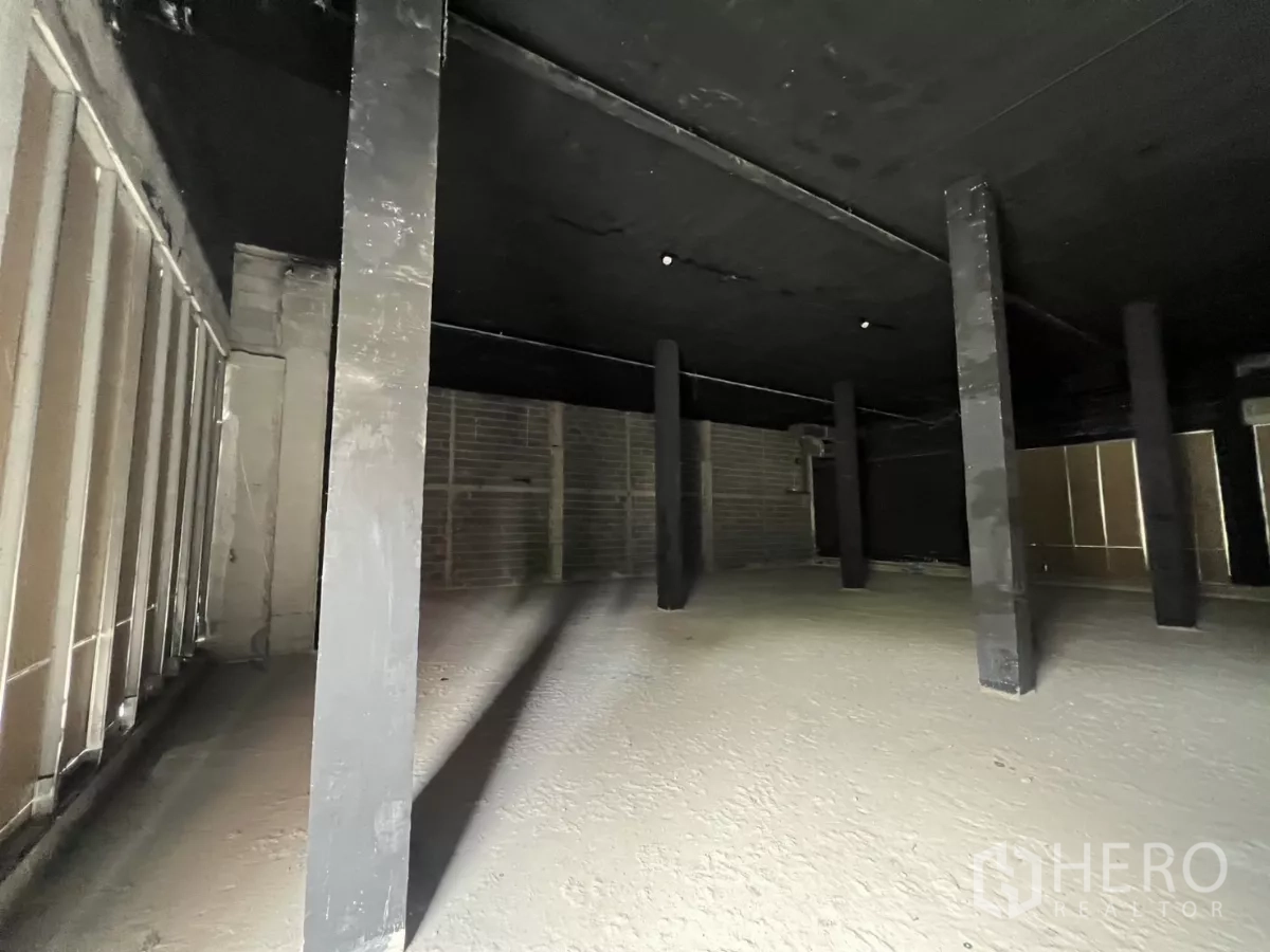 พื้นที่ขายปลีก ให้เช่า - ภายในร้านค้าที่ยังไม่ตกแต่ง เห็นเสารับน้ำหนัก เพดานสีดำ และพื้นดิบ