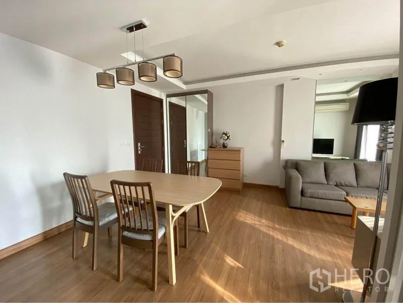 Condominium for rent in Huai Khwang, Bangkok - Dining area with pendant lights beside a sofa in the living room.