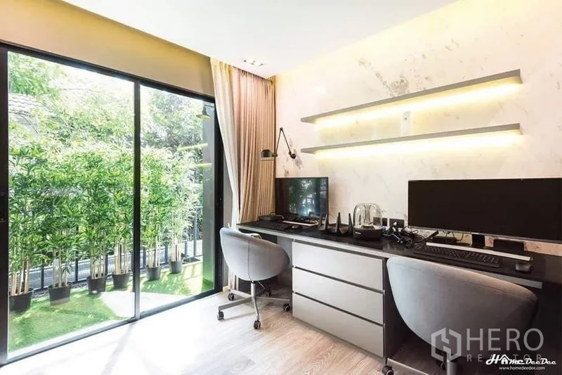 Townhouse for sale in Lak Si, Bangkok - Sunlit home office with long built-in desk by garden-view sliding doors.