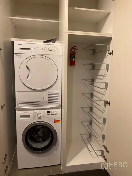 公寓 出租在Khlong Toei, Bangkok - 室内洗衣间，叠放式洗衣机与烘干机及内置收纳架。
