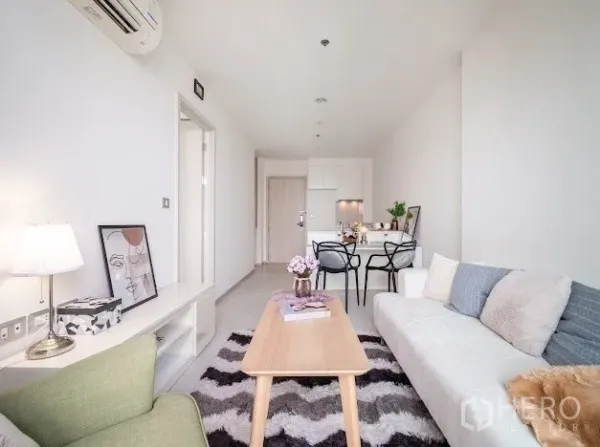 公寓 出售在Khlong Toei, Bangkok - 采光充足的开放式客餐厅，沙发、锯齿地毯与紧凑厨房，靠近BTS Ekkamai的素坤逸公寓。