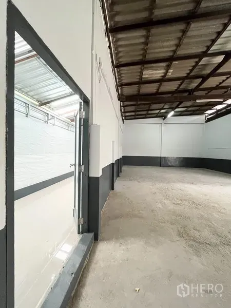 Warehouse for rent in Wang Thonglang, Bangkok - High-ceiling warehouse interior with concrete floor and two-tone white and dark trim walls.