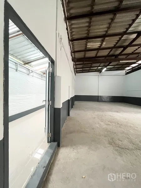 Warehouse for rent in Wang Thonglang, Bangkok - High-ceiling warehouse interior with concrete floor and two-tone white and dark trim walls.