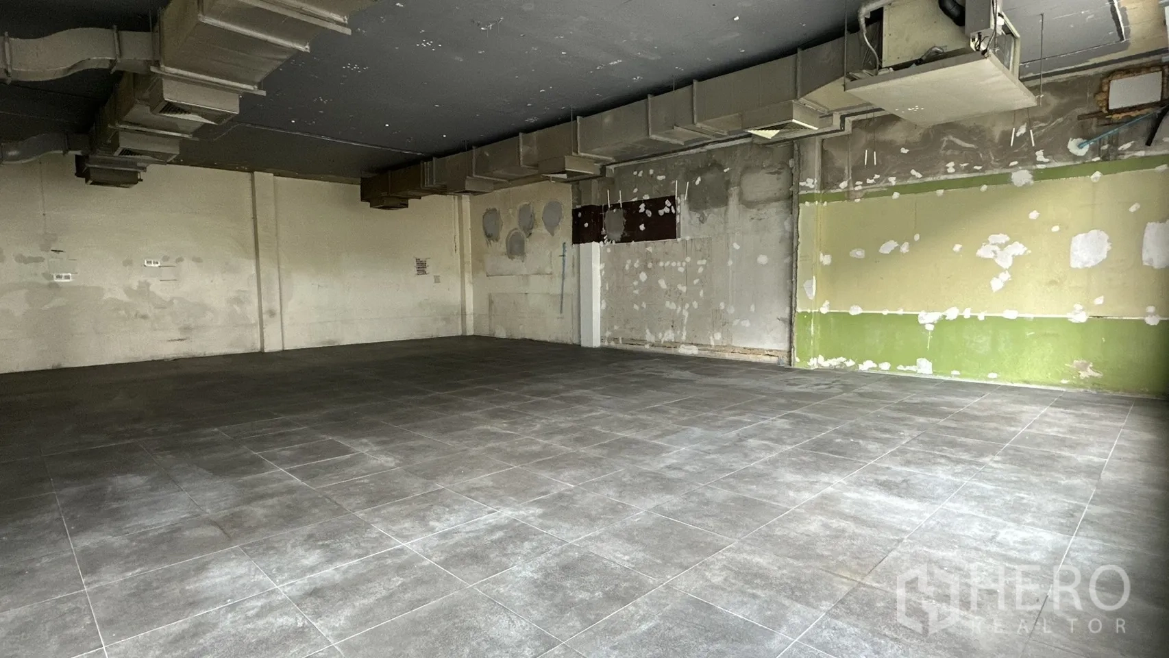 Retail Space for rent in Watthana, Bangkok - Corner of the unit showing unfinished walls and gray tile flooring.