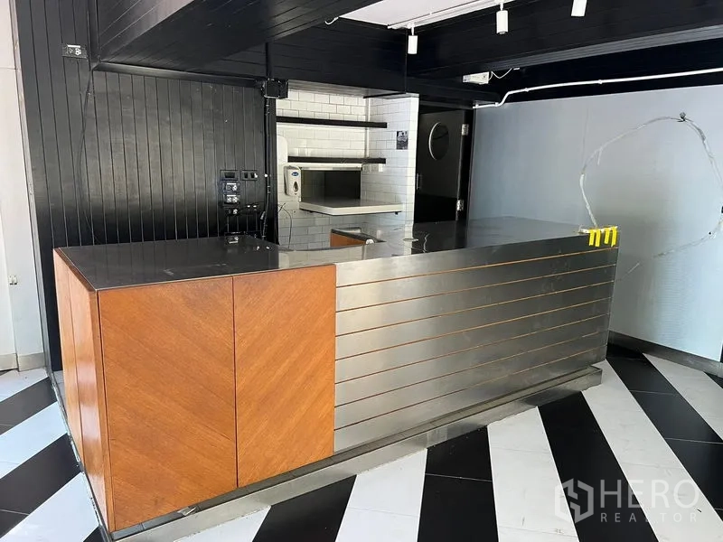 零售空间 出租在Bang Rak, Bangkok - 不锈钢与木质前台，后方白色瓷砖备餐区。