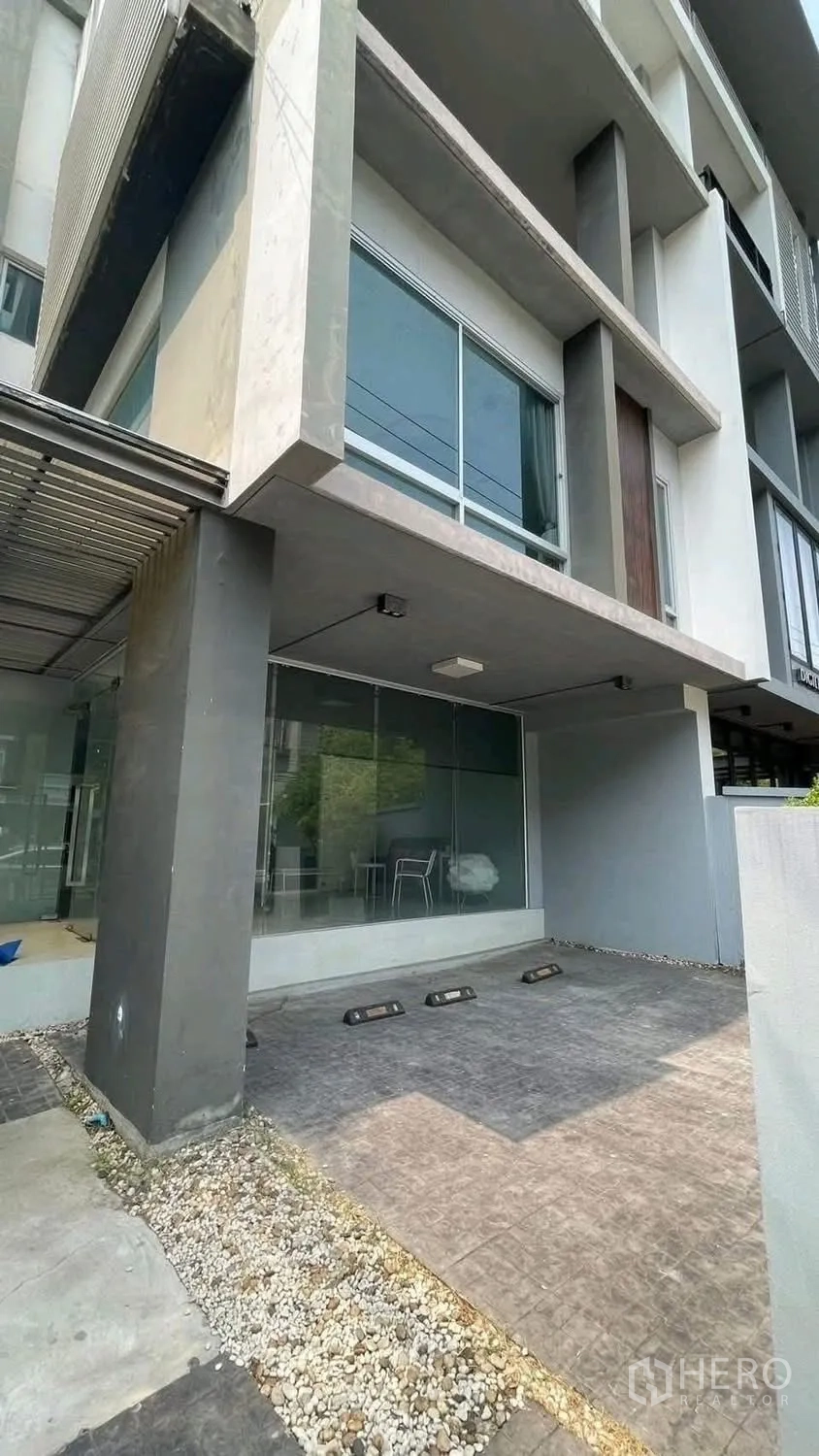 家庭办公室 for rent or sale in Wang Thonglang, Bangkok - 门前有顶停车位，玻璃立面与碎石铺地。