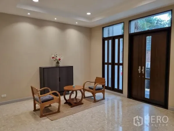 Detached House for rent in Bang Khae, Bangkok - Spacious foyer with high windows, wooden double doors, and a minimalist lounge set.