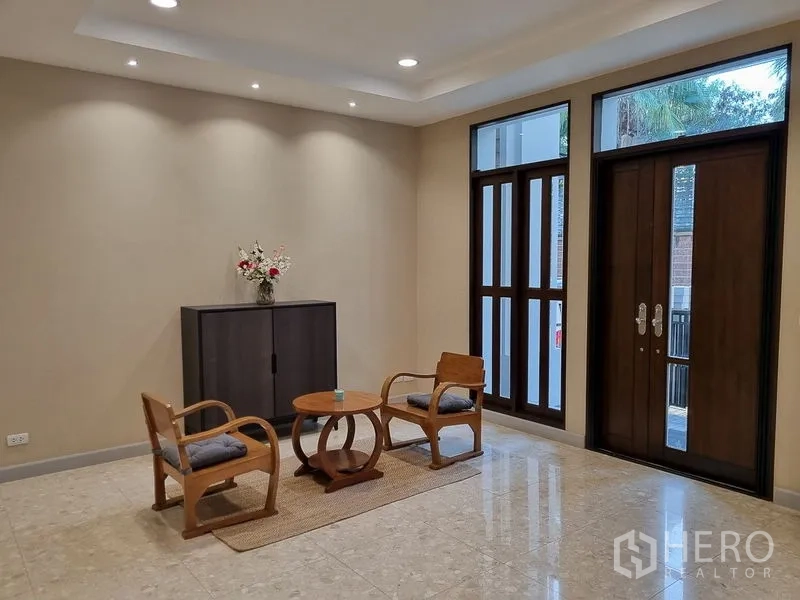 Detached House for rent in Bang Khae, Bangkok - Spacious foyer with high windows, wooden double doors, and a minimalist lounge set.