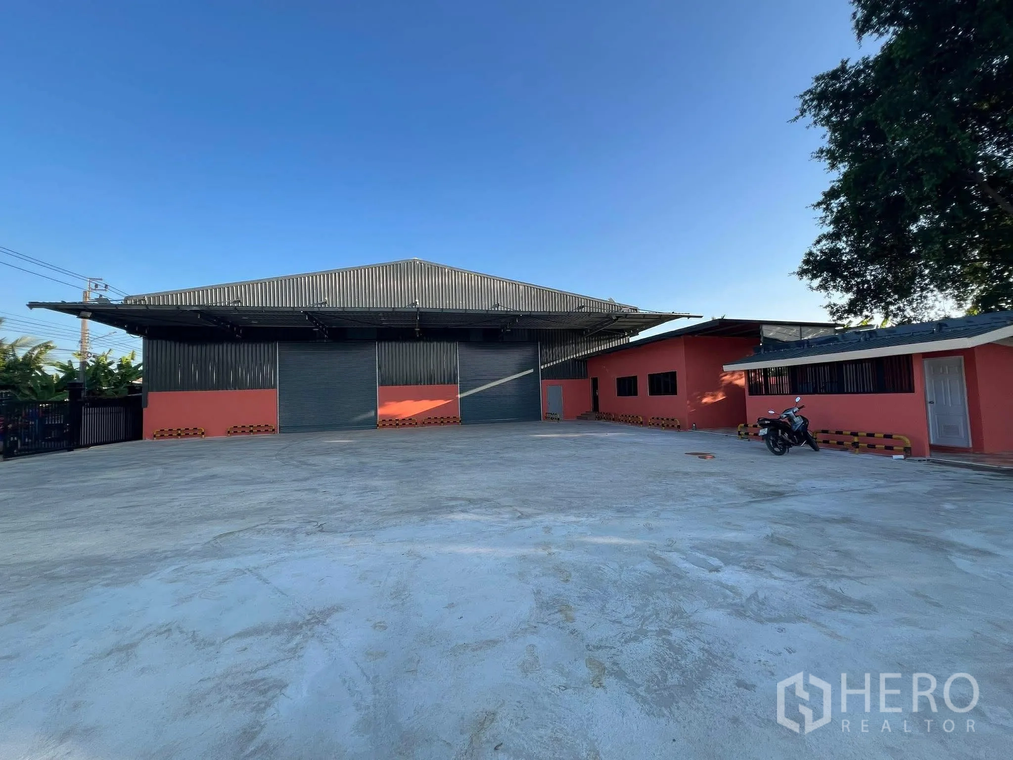 Warehouse for rent in Nong Chok, Bangkok - Warehouse exterior with wide concrete yard, multiple roller shutters, and an attached front building.