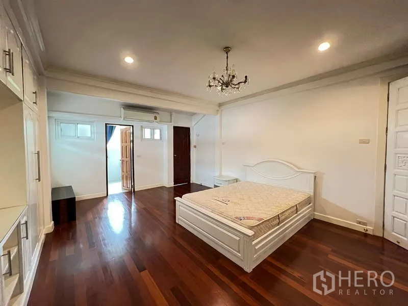 Detached House for rent in Chatuchak, Bangkok - Large master bedroom with white bed, nightstand and polished hardwood floors.