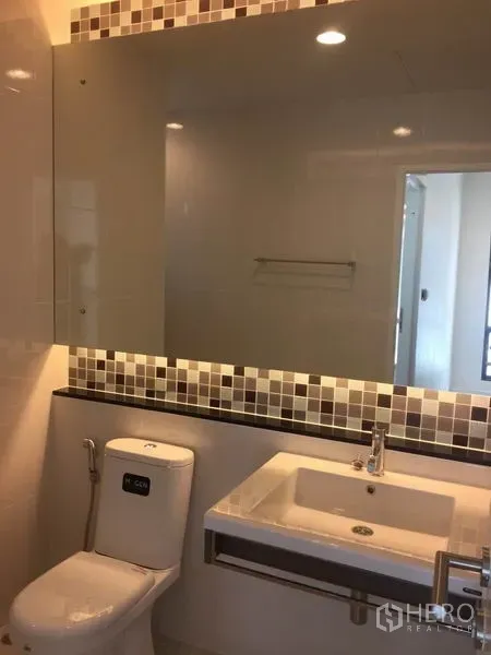 Detached House for rent in Bang Kapi, Bangkok - Bathroom with large mirror, mosaic tile trim, vanity sink and toilet.
